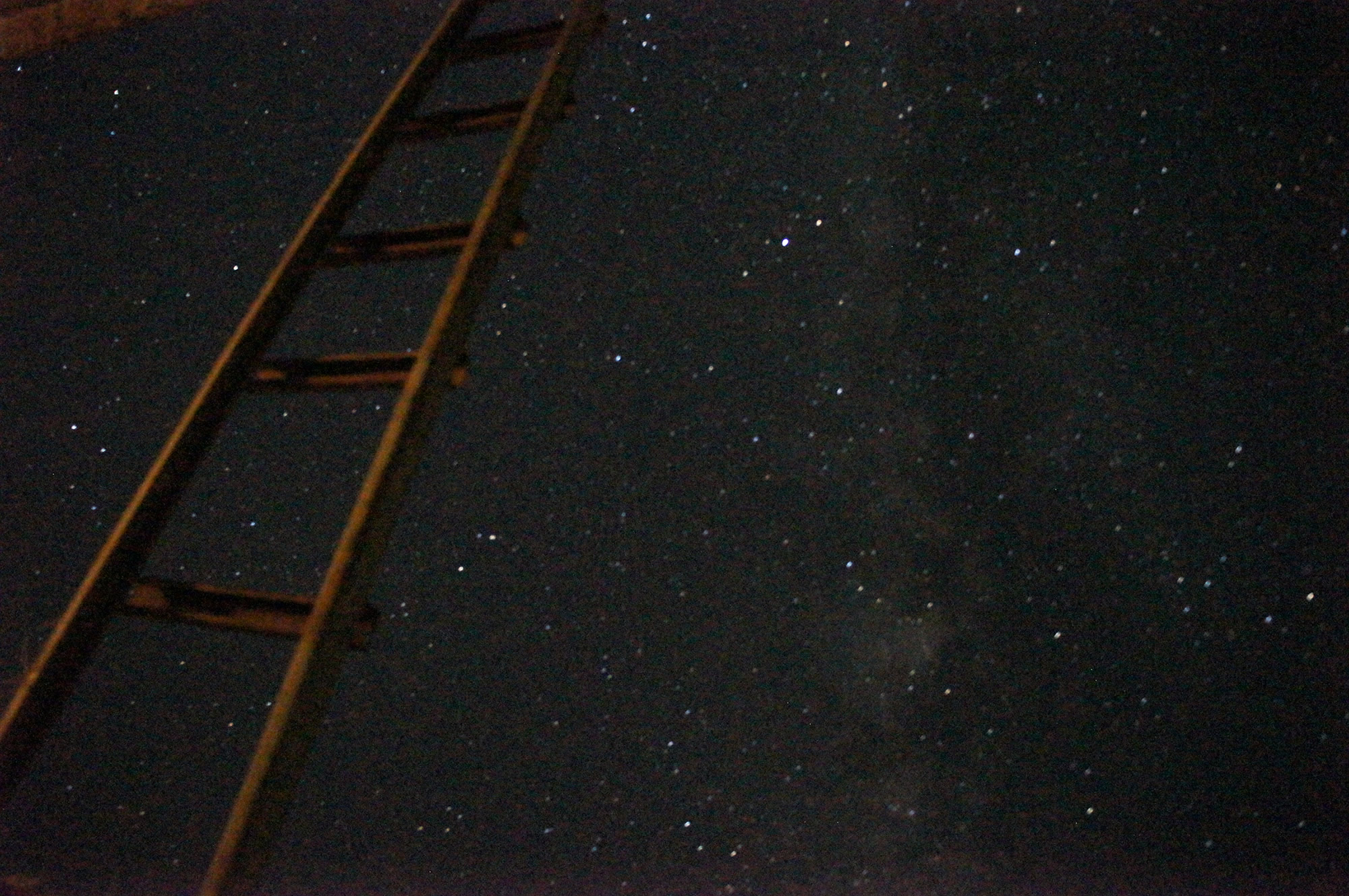 Bildmontage einer Leiter, die in den Sternenhimmel führt